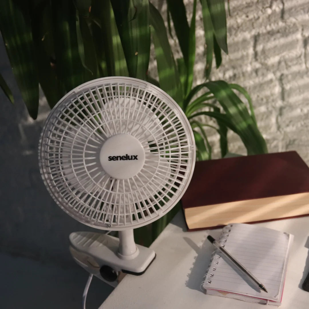 A photo of the Senelux clip on fan, attached to a desk in a brightly lit, cosy office
