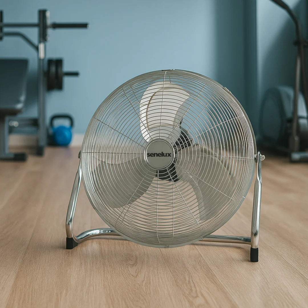 Floor fan with 'Senelux' branding on a wooden floor in a room with exercise equipment.