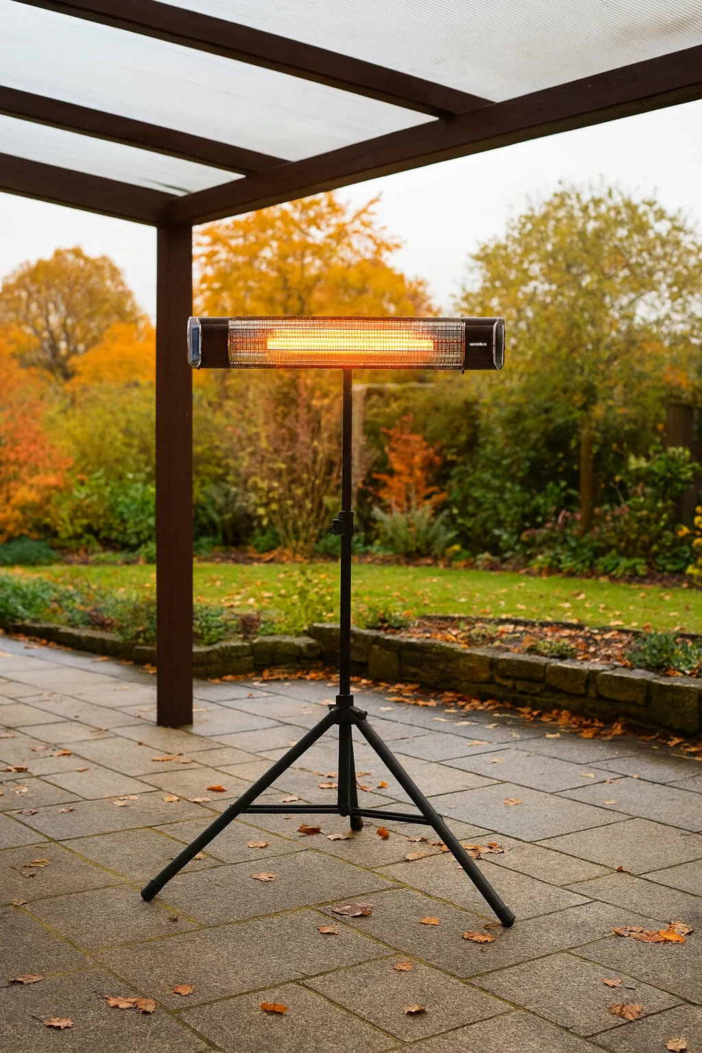 Outdoor patio heater on a stand in a garden setting with trees and grass.