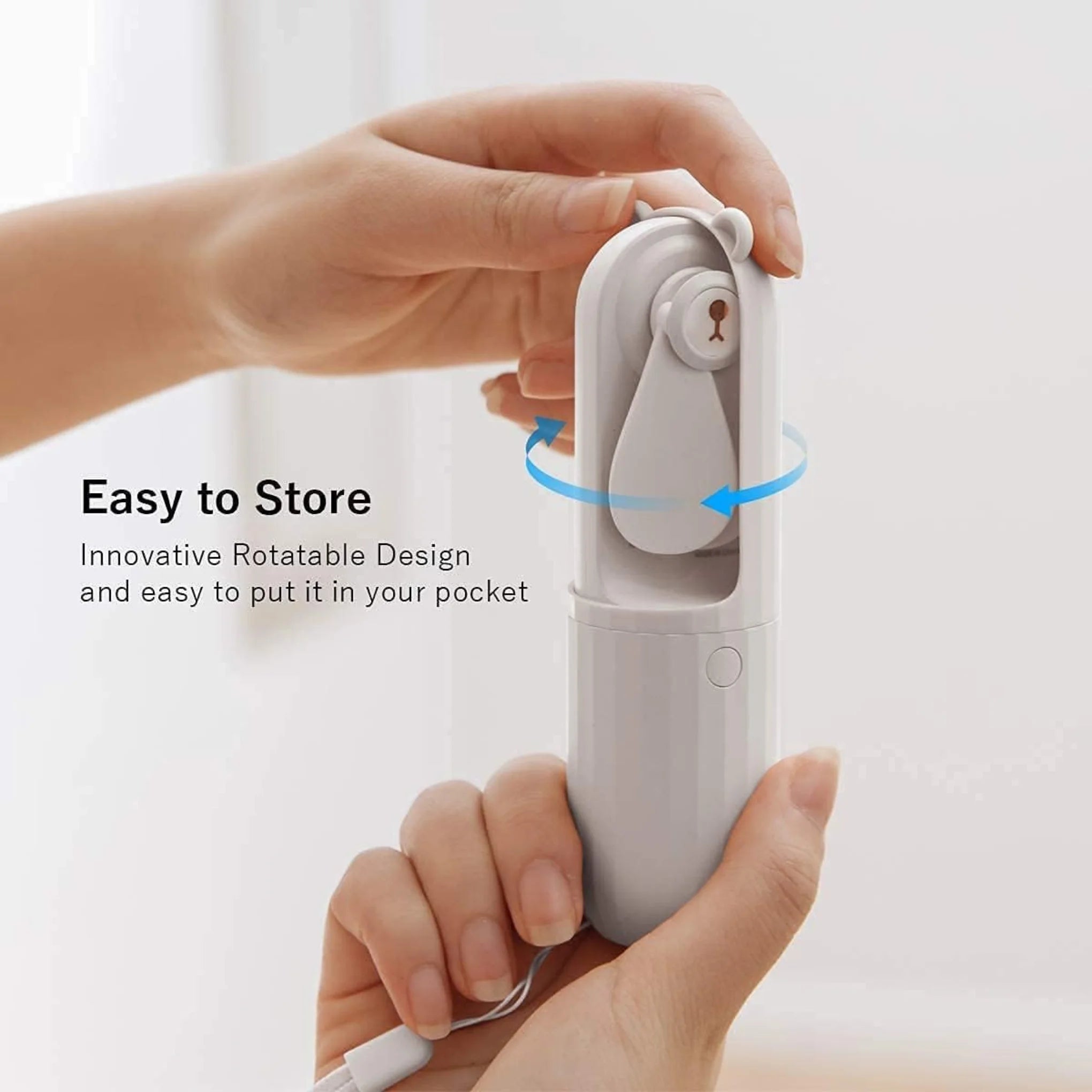 A close up of a pair of hands locking the white pocket bear fan showing that the top rotates to close and protect the fan