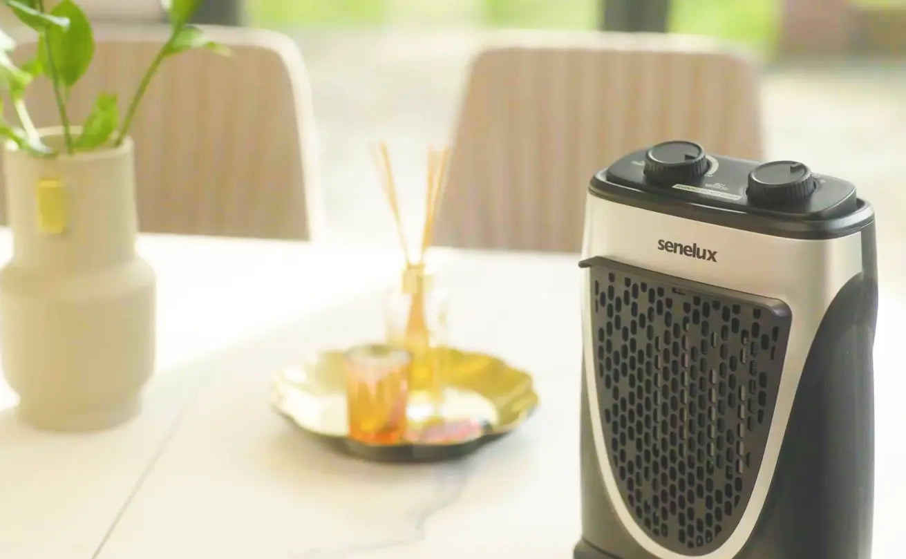 A picture of a Senelux Mini Heater resting on a table heating a room with high efficiency the black and silver design is on display