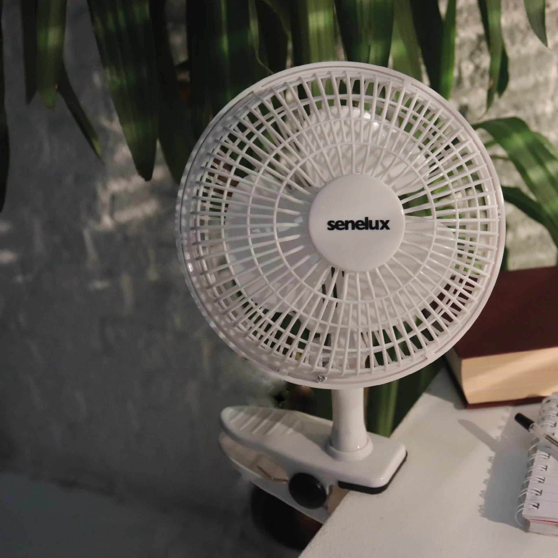 A photo of the Senelux 6" clip on fan, firmly clipped onto the side of a clean white desk.