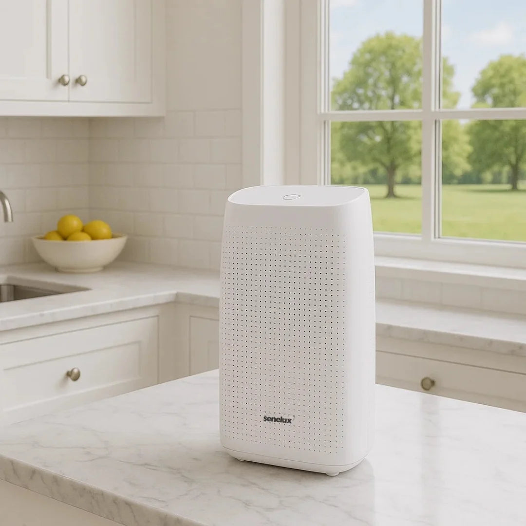 White Senelux dehumidifer on a kitchen counter with a window view of greenery