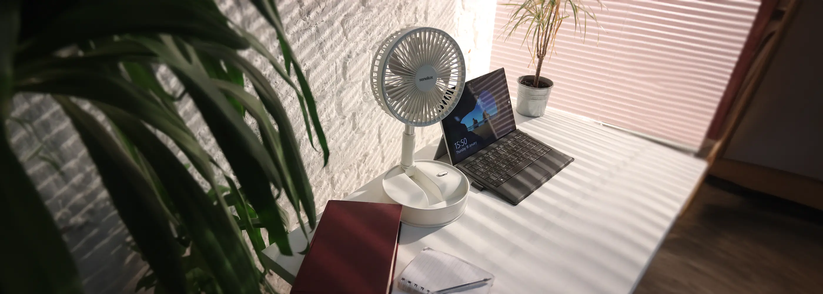 A photo of the Senelux rechargeable cooling fan sitting on a desk in a brightly lit, warm office