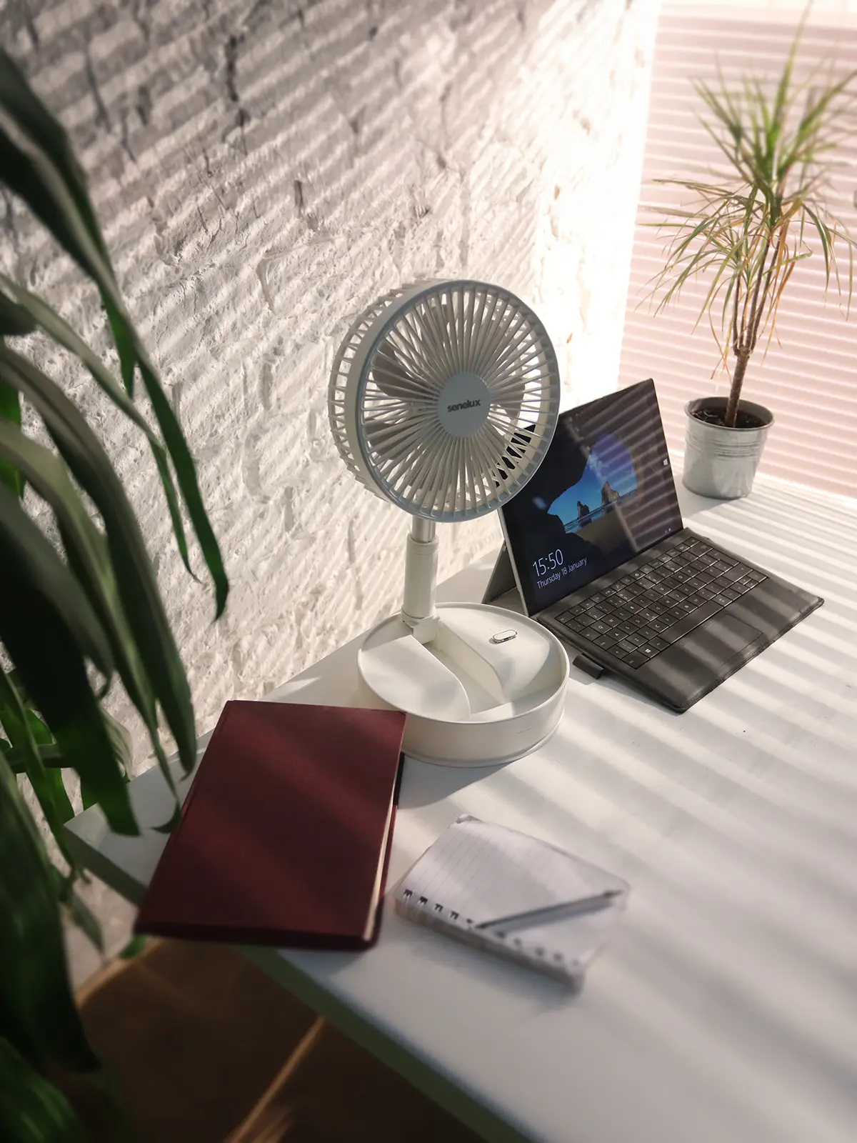 A photo of the Senelux rechargeable cooling fan sitting on a desk in a brightly lit, warm office